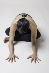Fototapeta na wymiar Portrait of mid Asian woman is playing yoga in studio in black sport wear.