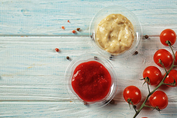 Tasty sauces in plastic bowls on table