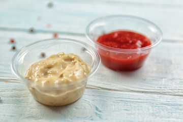 Tasty sauces in plastic bowls on table