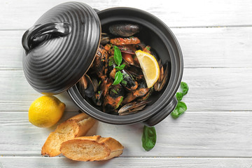 Pan with delicious mussels in tomato sauce on wooden table