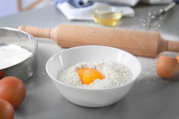 Bowl with flour and egg on kitchen table