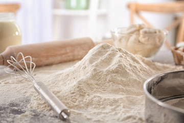 Heap of flour and whisk on kitchen table