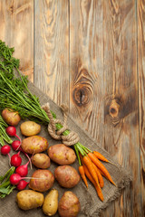 Potatoes, carrot and radishes. Raw new potato. Fresh natural vegetables. Organic food on wooden background.