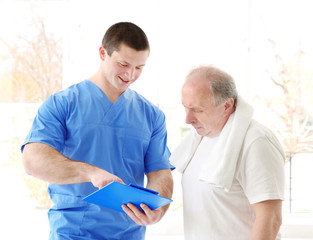 Physiotherapist with elderly patient in modern clinic