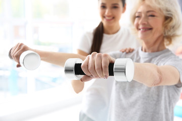 Physiotherapist working with elderly patient in modern clinic