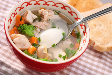 Plate with homemade chicken soup on table