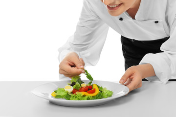 Obraz na płótnie Canvas Young female chef making salad on white background