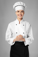 Young female chef on light background