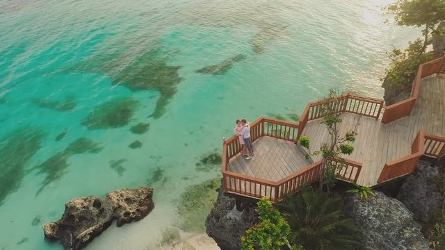 A beautiful light green coast with reefs and a loving couple on the balcony above the beach. The beautiful nature of the Philippines. Aerial view.
