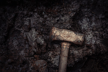 old rusty iron construction hammer on the mud, warm tone photography and film style.