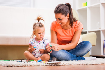 Mother and daughter in their home. They are playing with plasticine.