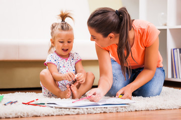 Mother and daughter in their home. They are looking at coloring book.