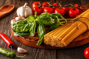 Products for cooking - pasta, tomatoes, garlic, pepper, and basil.