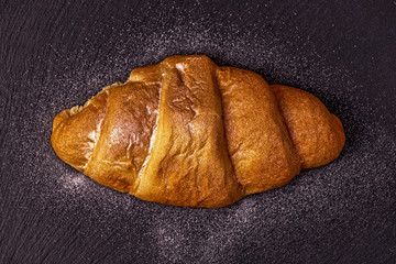 Fresh croissant on dark background.
