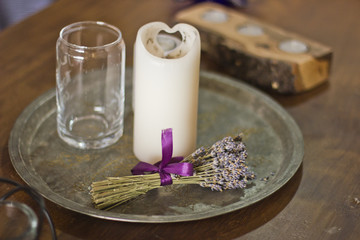 Obraz na płótnie Canvas A bunch of lavender and white candle and glass on a metal old aged tray