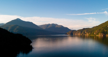 Aerial shot of ocean bay or lake with mountains while  sunset