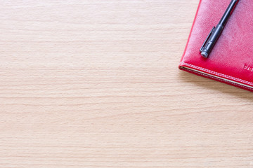 Red book with pen on table .Top view