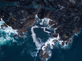 Aerial shot of waves hitting rocks on ocean coast