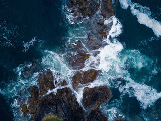 Fototapeta Aerial shot of waves hitting rocks on ocean coast obraz