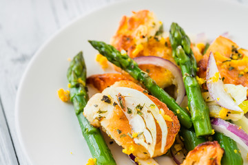 Salad with fried halloumi, asparagus and orange zest. Close up. White wooden background