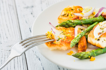 Salad with fried halloumi, asparagus and orange zest. Close up. White wooden background