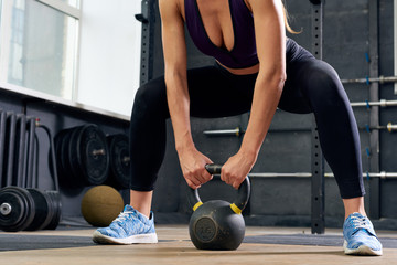 Young Woman Lifting Kettlebell in Squat