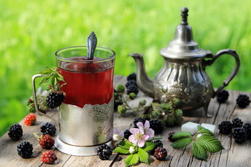 чай из ежевики со свежей ягодой на столе в саду