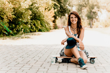 Fototapeta na wymiar Beautiful young woman sitting over a skateboard