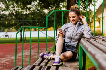 Attractive woman using a smartphone while sitting on a wooden bench in a park