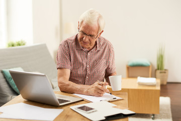 Fototapeta premium Senior Man Counting Taxes at Home