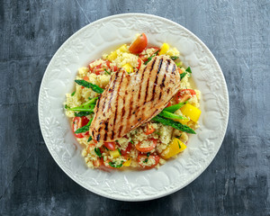 couscous salad with grilled chicken and asparagus on white plate. healthy food