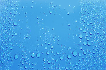 Naklejka na ściany i meble Water drops on smooth surface, blue background