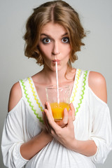 Young girl drinking fresh orange juice through a straw . Eyes wide open