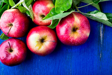 Red apples on blue wooden background. Top view. Copy space.