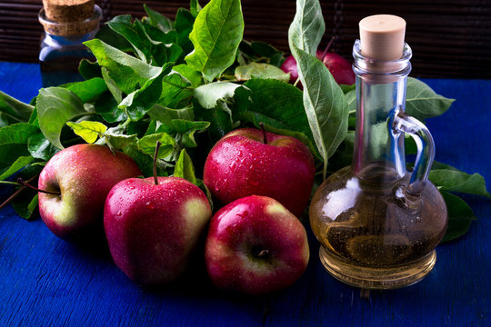 Apple cider vinegar. Three glass bottle on blue background. Red apples