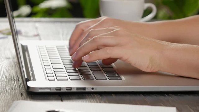 Hands typing at laptop keyboard
