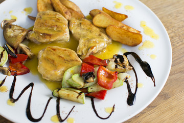 Grilled chicken breast with vegetables and sauce on a plate. Traditional cuisine. Grill kitchen.