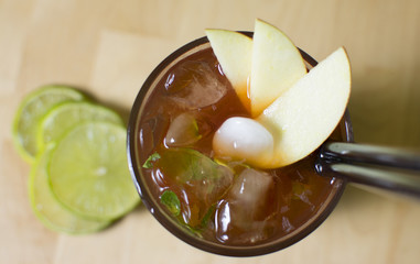 Cocktail on a wooden table. Mint, lime, ice ingredients, and bar table.