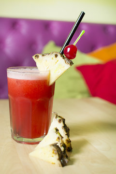 Cocktail on a wooden table. Cherry's and pineapples stabbed with a toothpick.