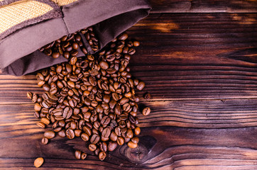 Roasted coffee beans in sack on wooden table. Top view