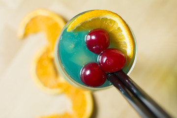 Cocktail on a wooden table. Cherry's, lemons and ice.