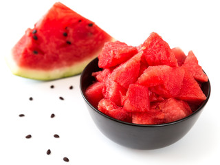 Pieces of ripe watermelon in a cup on a white background