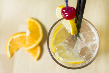 Cocktail on a wooden table. Cherry's, lemons and ice.
