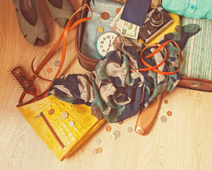Preparation for a travel. Outfit of young woman in vintage style. Different objects on wooden surface.