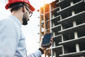Professional male engineer with modern tablet on construction site. Modern engineer builder checks...