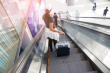 BANGKOK, THAILAND - AUGUST 8, 2017: Blurred background of asian woman with luggage suitcase on escalators at Suvarnabhumi Airport. The most popular SE Asia aviation hub.