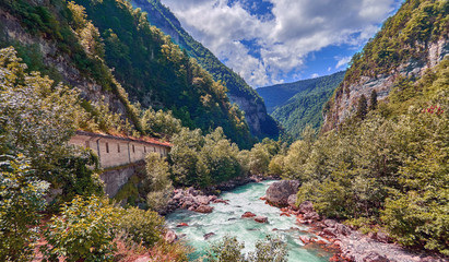 Mountain fresh and cold river in summer time under cloudy sunny blue sky