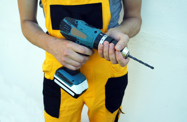 Fototapeta premium Pracownik trzyma śrubokręt elektryczny, z bliska, białe tło ściany