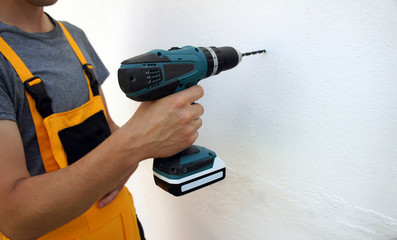 Man using an electric screwdriver, close up, white wall background