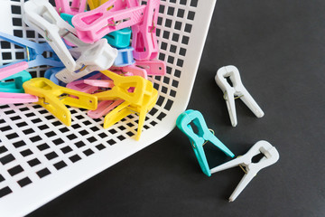 Colorful plastic clothespins coming out of plastic basket 